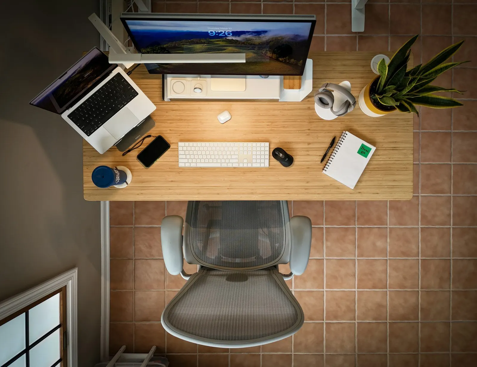 Bureau individuel vu d'en haut, ordinateur portable, écran, clavier, carnet et fauteuil vide