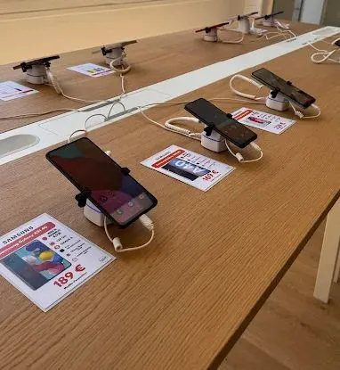 Table en bois clair où des smartphones reconditionnés sont posés sur des supports, avec leur étiquette de prix
