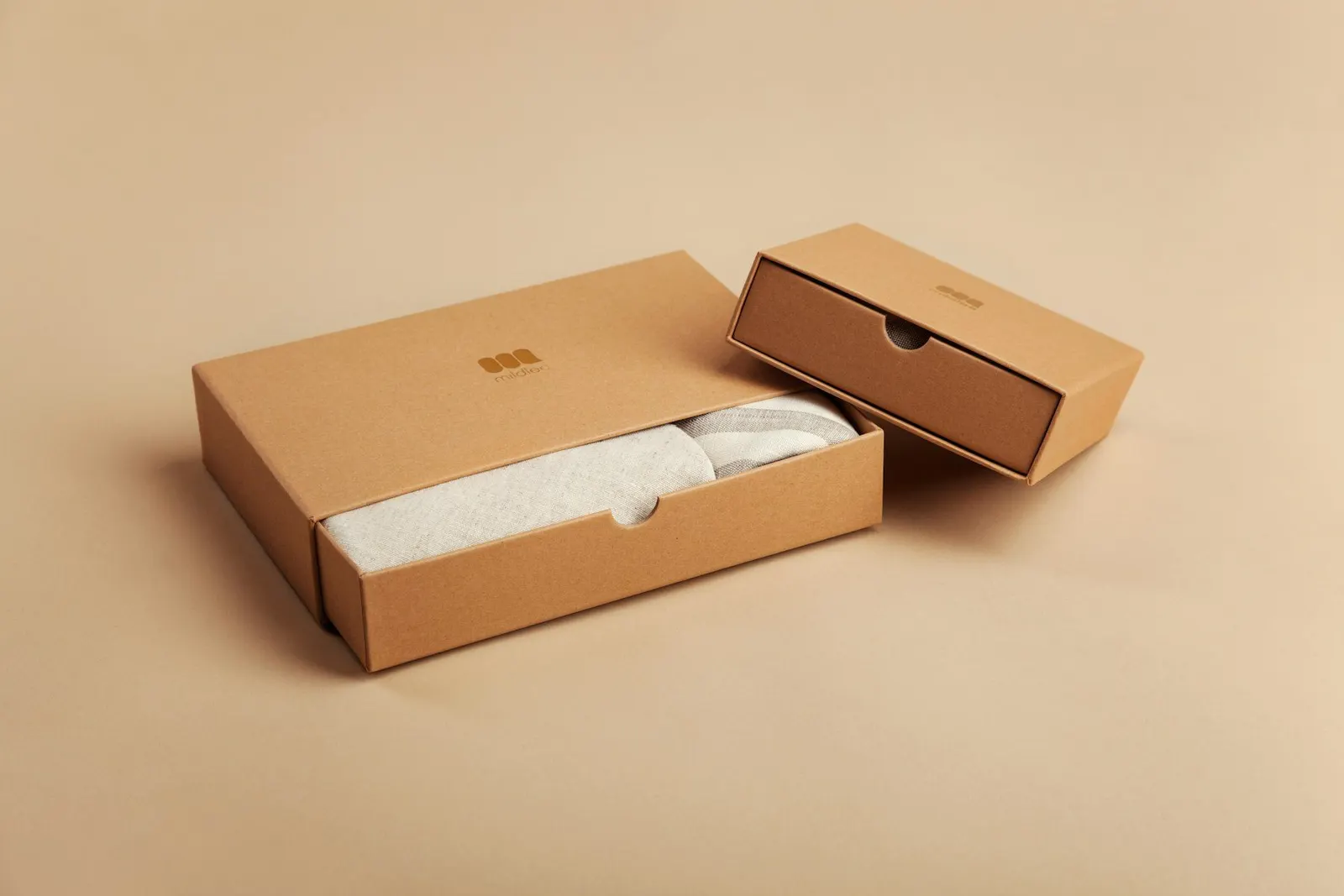 Coffret d'expédition en carton kraft entrouvert sur un fond beige, prêt pour un envoi de commande