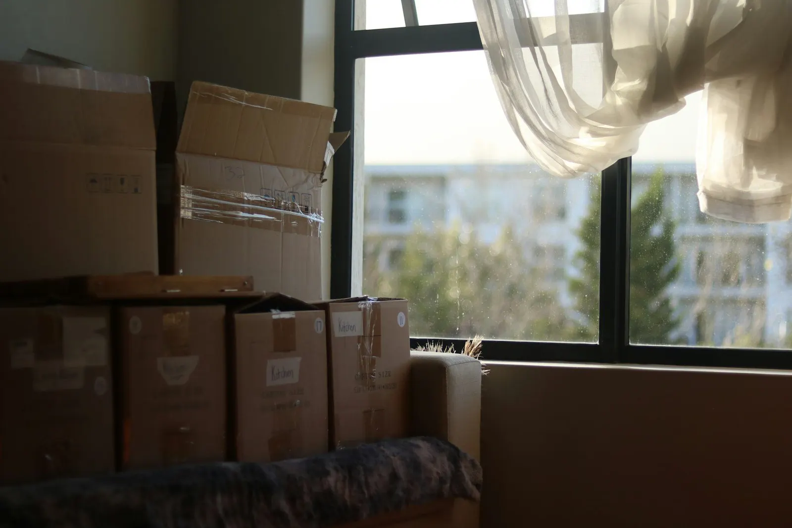 Cartons de déménagement empilés près d'une fenêtre dans une pièce presque vide