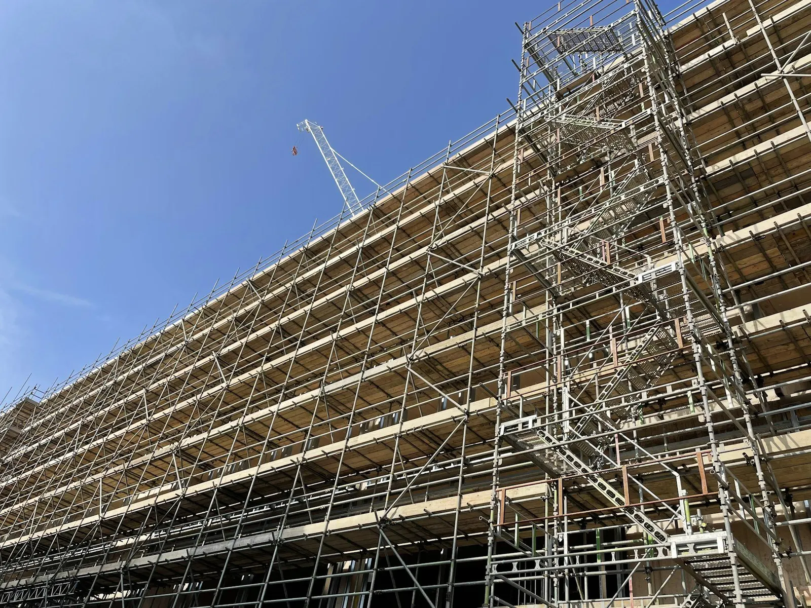Façade d'immeuble entièrement couverte d'échafaudages pendant sa rénovation, vue en contre-plongée